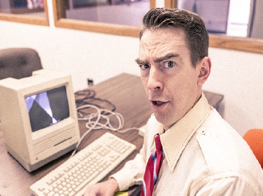 mies istuu retromallisen tietokoneen edessä